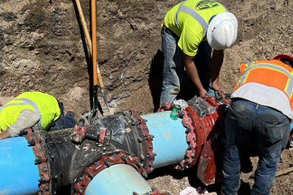 Crew assembling restrained fittings on water main
